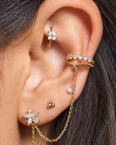 Curated ear with diamond flower studs, a huggie hoop and a chain ear cuff