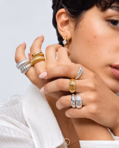 Stacked ribbed gold and silver dome rings worn on a hand